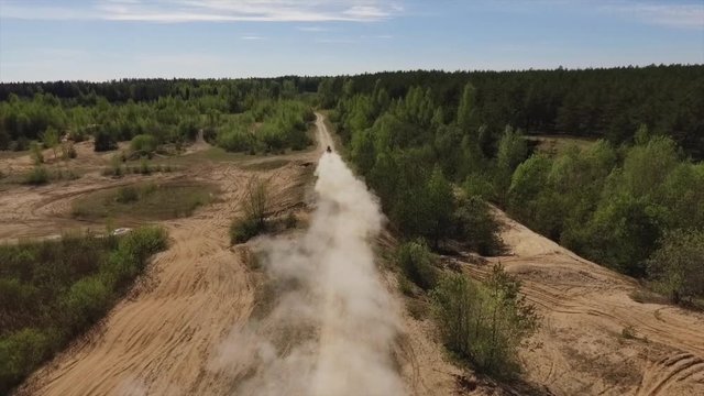 Aerial of a man speeding away offroad on a quad bike, leaving a dust cloud behind him