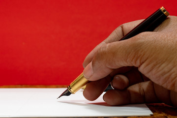 close up of human hand holding a gold and black founain pen