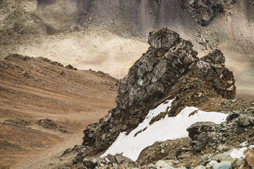 Atmospheric alpine landscape with firn or snow near stony cliff close-up on mountain wall...