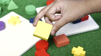 Image of a kid's hand playing with colorful wood block