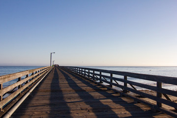 Fototapeta na wymiar Long Wooden Pier with Shadows and Ocean During Dusk