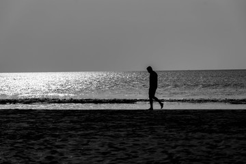 Fototapeta na wymiar Sad man walking on the beach