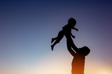 Father and son plays against sunset sky