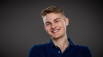 Obraz premium A handsome young man laughs as he sits in a relaxed manner