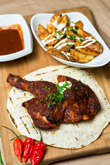 fried chicken legs served on flatbread, a plate of potatoes and tomato sauce