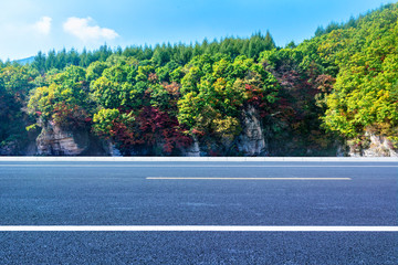 The highway at the foot of the blue sky mountain in autumn.