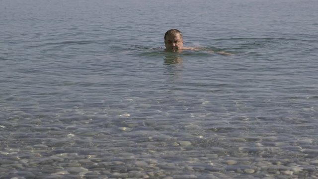 frightened man escapes from a shark when swimming in the sea. man turns his head back and feel shock seeing shark.