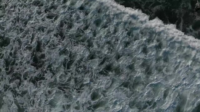 Top Down Drone Aerial View Of Swirling Dark Blue Ocean Water As Waves Pass Underneath The Camera