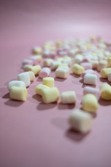 Fototapeta na wymiar Tiny and colorful marshmallows on pastel pink surface