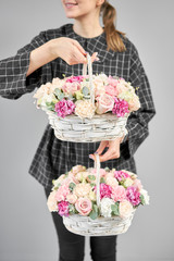 Two Flowers arrangements in Wicker basket. Modern floral shop. Finished work of the florist. Cute bouquet of mixed flowers in womans hands. Delivery fresh cut flower from online store