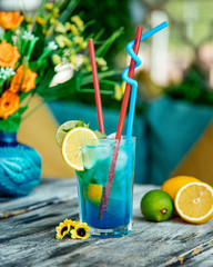 blue cocktail glass with lime and lemon
