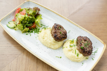 Delicious juicy meat cutlets, mashed potatoes sprinkled with greens and fresh healthy salad of tomatoes and lettuce leaves.