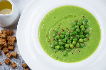 Close-up of cream-soup with green peas served in a white plate, selective focus, elevated view