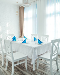 restaurant room with white table and chairs and blue napkins