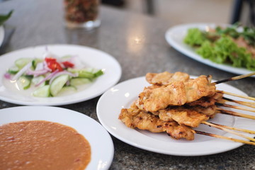 Pork satay or Grilled pork stick on the table served with peanut sauce or sweet and sour sauce appetizer dish of traditional Thai street food recipe , Thailand street food Travel concept