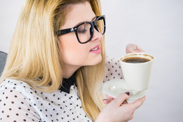 Happy woman at office drinking hot coffee