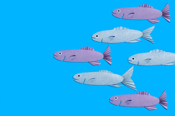 Handmade paper school of fish on blue background