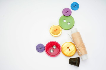 Sewing supplies. Thimble, thread, needle and different buttons on a light background.
