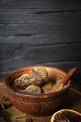 Craft chocolate truffles in vintage clay Cup on dark wooden background