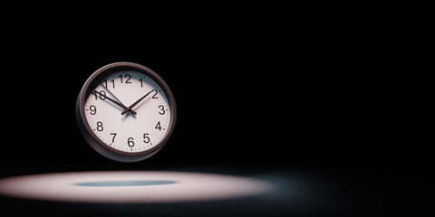 Fototapeta premium Clock Spotlighted on Black Background
