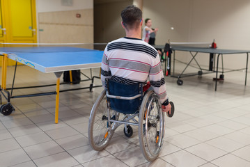 Wheelchair user playing table tennis. From the back.