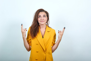 Attractive young woman in yellow jacket keeping finger up, looking pretty isolated on gray...