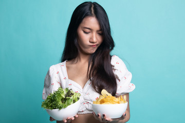 Young Asian woman with potato chips and salad.