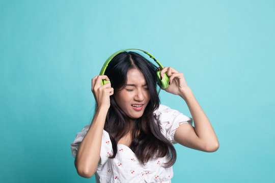 Too loud.  portrait of  young asian woman  holding  headphones and making unhappy face.