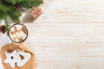 Hot Christmas drink with marshmallows in an iron mug and gingerbread cookies, on a white table. New Year, holiday background, copy space.