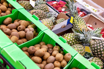 Pineapples and kiwi in boxes on the counter in the supermarket. Healthy eating. Close-up.