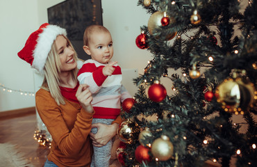 Mother and her baby decorate christmas tree