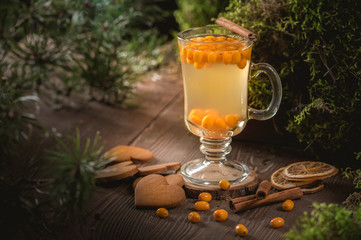 Hot spicy tea with sea buckthorn in glass cup on dark background