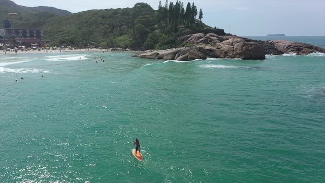 Man surfs towards crowded beach, Joaquina Beach, Florianópolis, Brasil