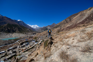 Naklejka premium Trekker on cliff looking at view of mountain, Annapurna Conservation Area, Nepal