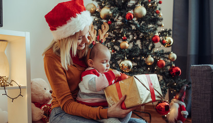 Young mother and baby open the christmas present