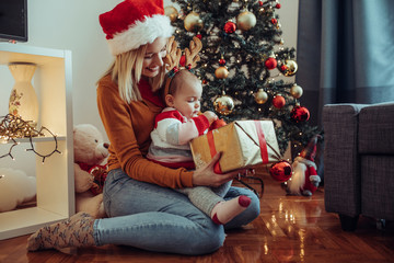 Young mother and baby open the christmas present