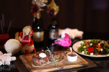 Rib eye steak on the christmas table. Steak rib eye roast on a wooden board with sauce and salt. Beef steak on wooden plate.