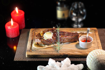 Rib eye steak on the New Year's table. Steak rib eye roast on a wooden board with sauce and salt. Beef steak on wooden plate.