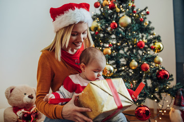 Young mother and baby open the christmas present