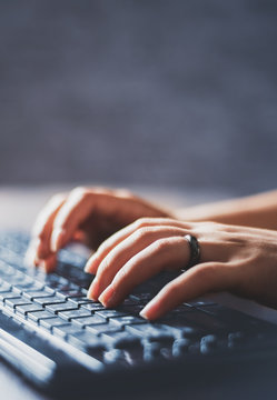 Woman working at home office hand on keyboard close up on wooden table background