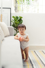 Portrait of little girl standing behind sofa in living room.