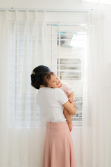 Portrait of happy vietnamese mother hugging with her cute little daughter at home