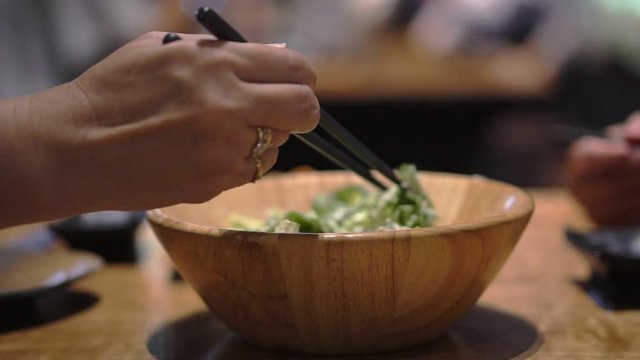 4K Video Unfocused  close up senior couple hands eating dinner together in Japanese restaurant using chopstick for salad and Taraba red king crabs