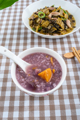 A plate of sauerkraut fried lean meat and a bowl of sweet potato porridge on the table