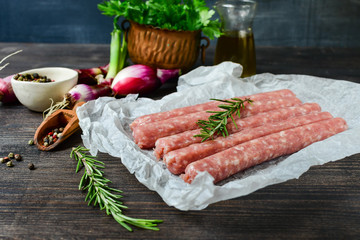 raw meat sausages for barbecue or hot dog. purple onions, salt and pepper, fresh oregano for marinade. grill  family dinner, healthy eating, keto diet food, meat recipe. Top view with copy space