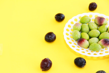 natural round green and brown olives in a decorative plate on a yellow background