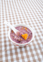 A bowl of nutritious and healthy purple potato porridge on a plaid table