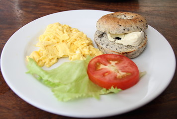 Toasted bagel with cheese, scrambled egg and salad