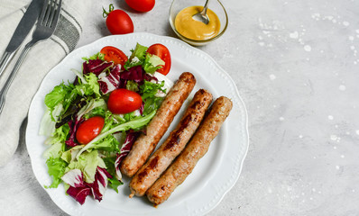 Healthy lunch grilled chicken sausages with tomato arugula salad. Top view copy space, chicken lunch recipe
