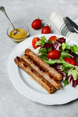 Healthy lunch grilled chicken sausages with tomato arugula salad. Top view copy space, chicken lunch recipe